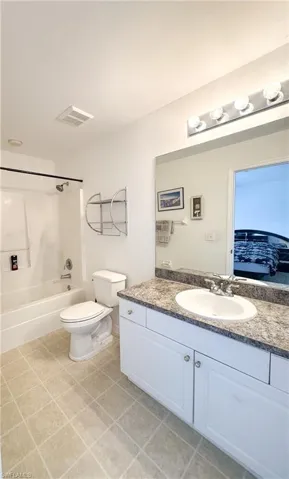 Full bath with visible vents, washtub / shower combination, toilet, tile patterned floors, and vanity