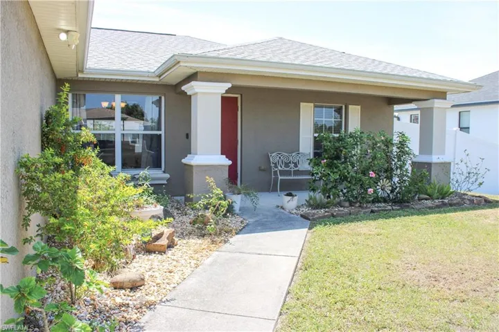 View of front of property featuring stucco siding, a porch, a shingled roof, and a front yard