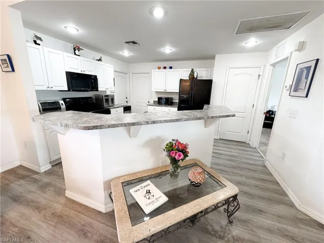 Kitchen featuring a breakfast bar, black appliances, and visible vents