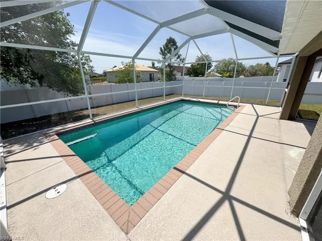 View of pool featuring glass enclosure, a patio area, a fenced backyard, and a fenced in pool