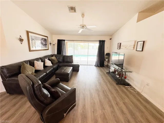 Living area featuring vaulted ceiling, wood finished floors, a ceiling fan, and visible vents