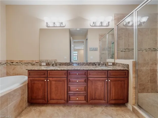 Bathroom featuring tile patterned flooring, shower with separate bathtub, vanity, and a chandelier