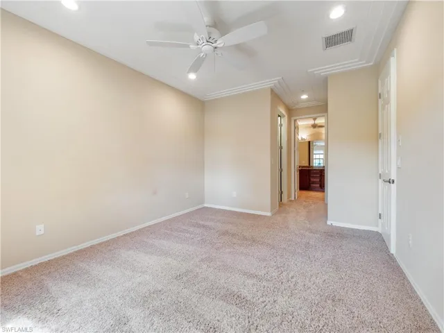Empty room with ceiling fan, light colored carpet, and crown molding
