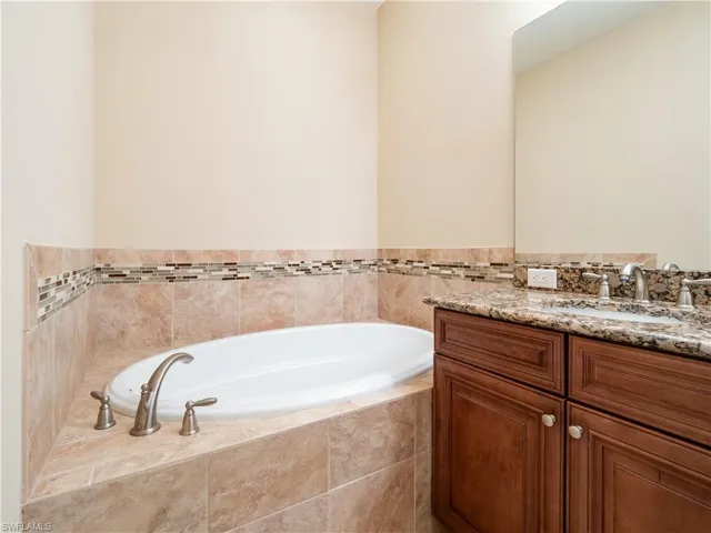 Bathroom featuring tiled bath and vanity