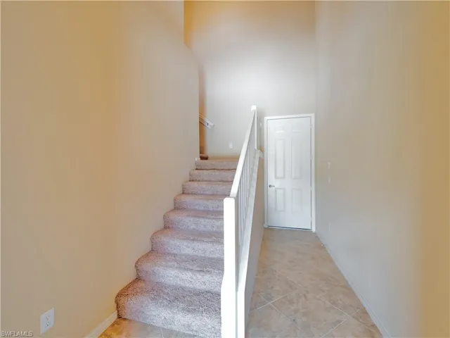 Stairway with a towering ceiling and tile patterned floors