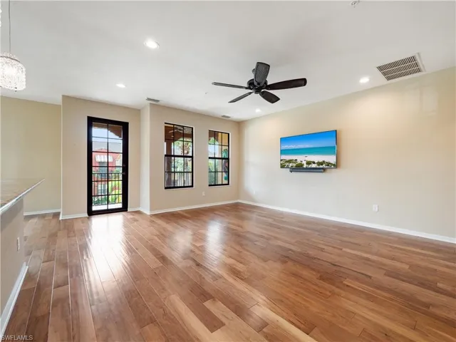 Unfurnished living room with ceiling fan with notable chandelier and hardwood / wood-style floors