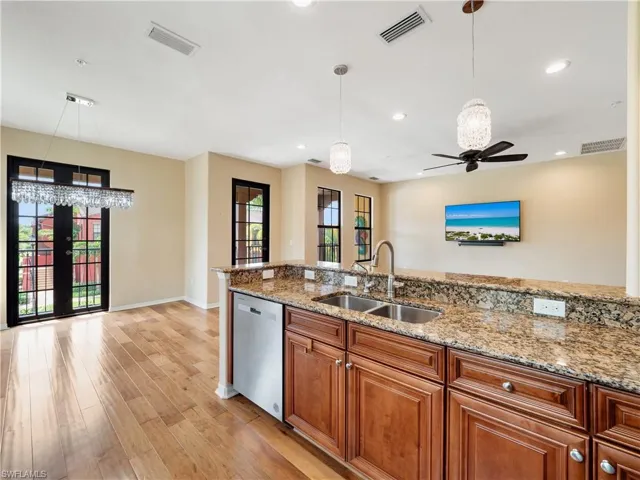 Kitchen featuring light hardwood / wood-style flooring, light stone counters, sink, ceiling fan, and stainless steel dishwasher