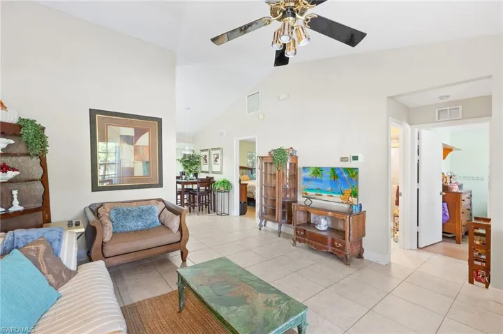 Living room featuring light tile patterned floors, high vaulted ceiling, visible vents, and a ceiling fan