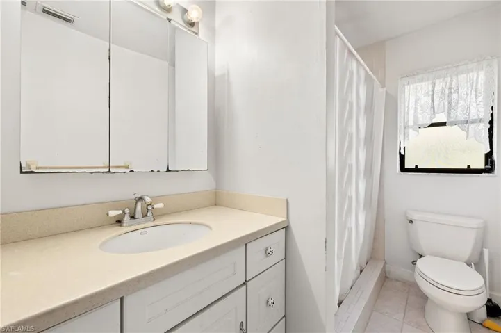 Bathroom featuring vanity, toilet, a shower with shower curtain, tile patterned floors, and visible vents