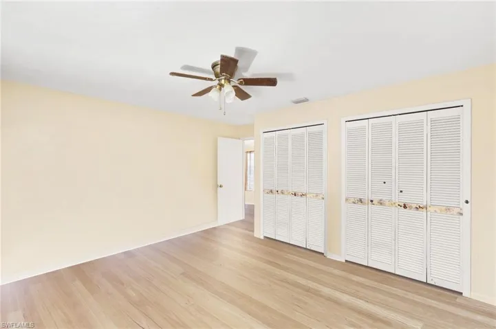 Unfurnished bedroom with light wood-style flooring, baseboards, two closets, and a ceiling fan