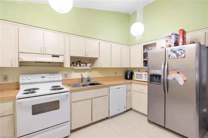 Kitchen with light countertops, a sink, open shelves, under cabinet range hood, and white appliances