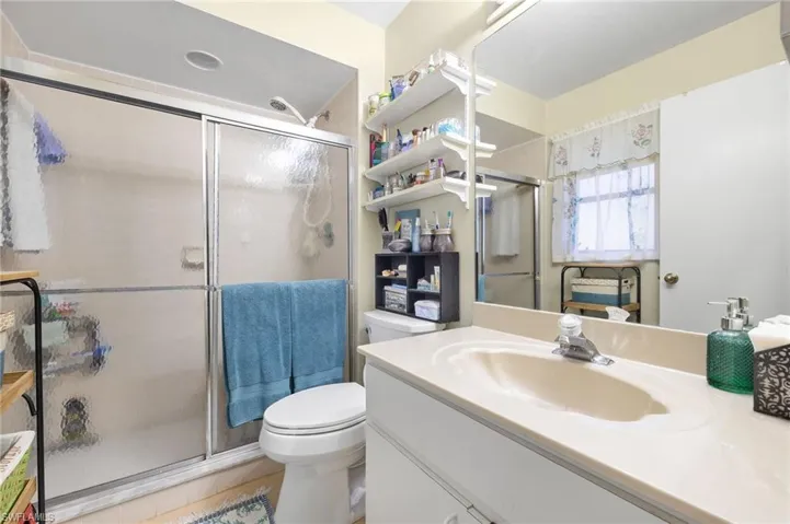 Bathroom with toilet, vanity, and a stall shower