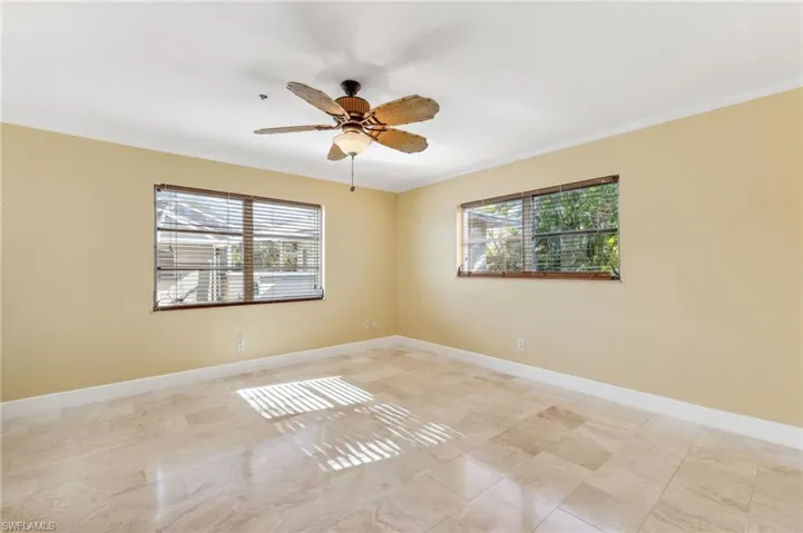 The Captiva unit guest bedroom featuring a ceiling fan, tile floors, baseboards, and crown molding
