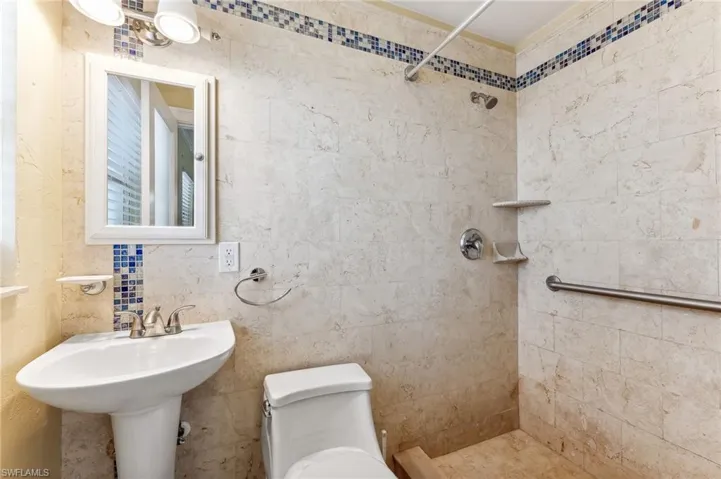 Primary Bathroom featuring toilet, a sink, and walk-in tiled shower