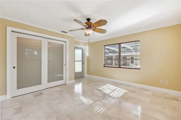 The Captiva unit Primary Bedroom featuring a closet, exterior exit, en-suite bath, tile floors, ceiling fan, crown molding, and baseboards
