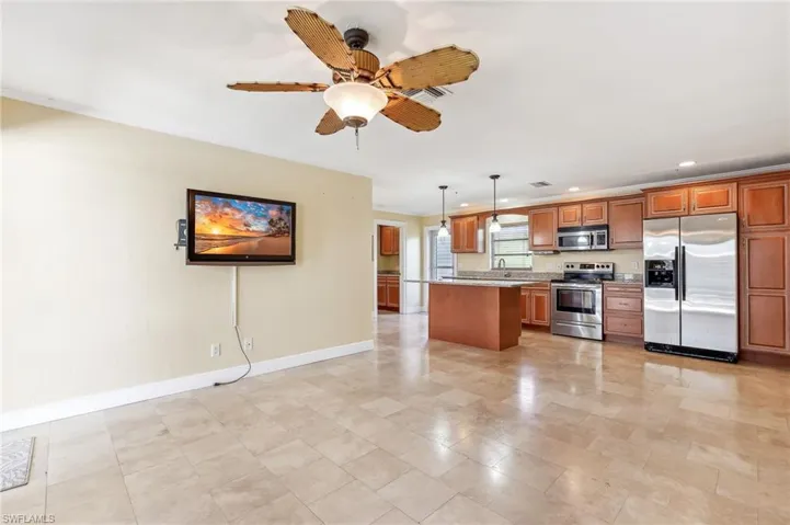 The Captiva unit kitchen and living area with baseboards, brown cabinetry, appliances with stainless steel finishes, pendant lighting, tile floors, and a sink