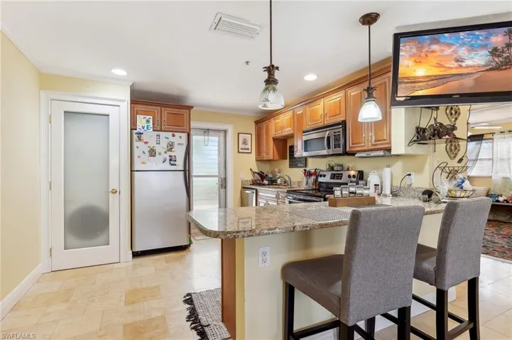 The Boca unit kitchen with stainless steel appliances, a peninsula, a kitchen bar, laundry closet, and tile floors