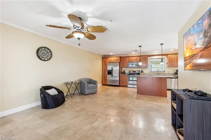 The Del Rey unit living room area with baseboards, crown molding, tile floors, and a ceiling fan.