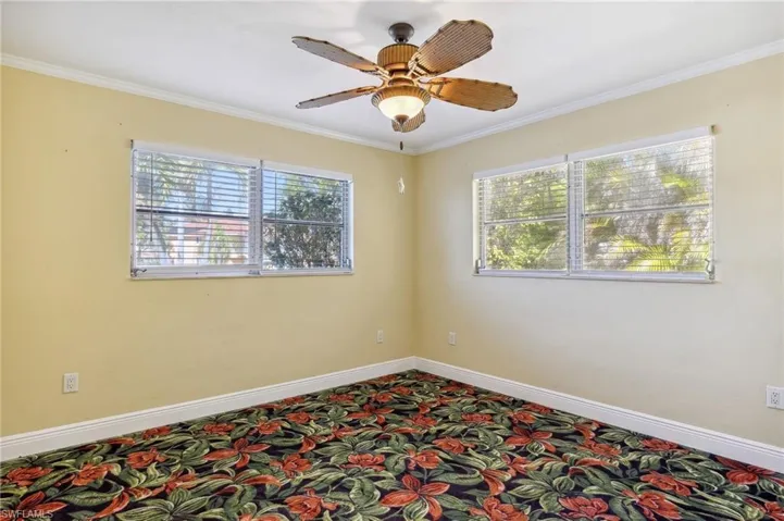 The Aruba unit guest bedroom with crown molding, ceiling fan, and carpet flooring