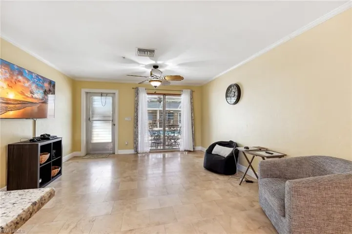 The Del Rey unit living room area with baseboards, crown molding, tile floors, and a ceiling fan.