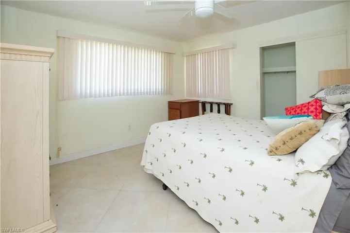 Bedroom with light tile patterned flooring, baseboards, a closet, and a ceiling fan