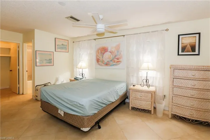 Bedroom featuring a textured ceiling, visible vents, a ceiling fan, and light tile patterned floors