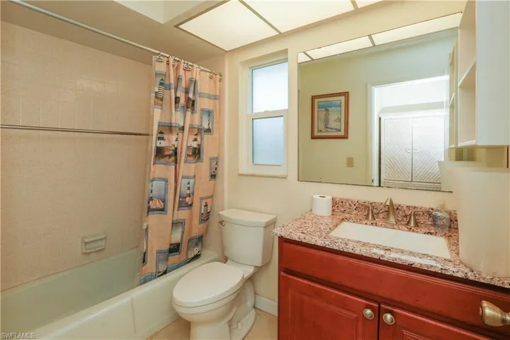 Full bathroom with toilet, vanity, and shower / bath combo with shower curtain