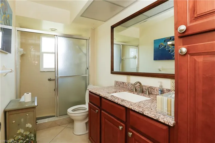 Bathroom with toilet, a stall shower, tile patterned floors, and vanity
