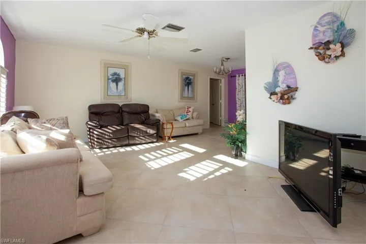 Living area with light tile patterned flooring, baseboards, visible vents, and ceiling fan
