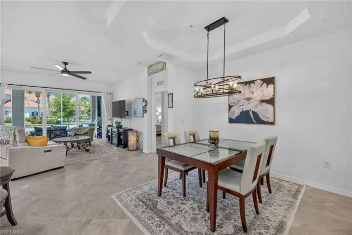 Open-concept living and dining area featuring large format tile flooring and a decorative tray ceiling