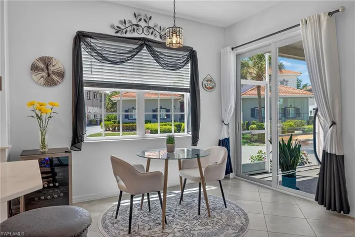 Bright dining area with large windows, sliding glass door access, tiled flooring, and a built-in beverage cooler