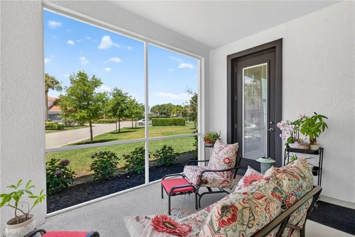Screened porch featuring a textured stucco exterior, a dark-framed door with a clear glass panel, and a concrete floor