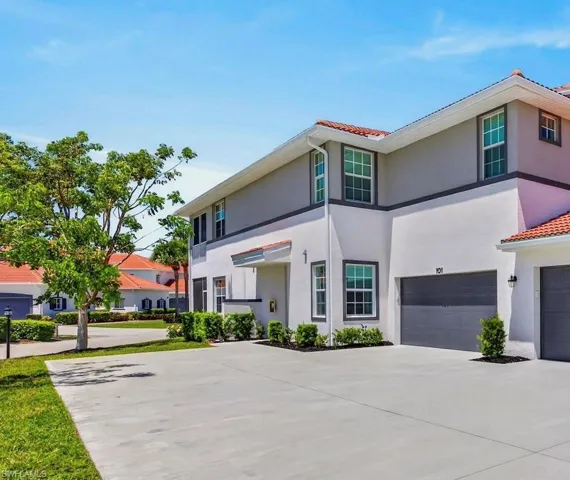 Stucco-finish exterior featuring a tile roof, an integrated two-car garage, and a concrete driveway