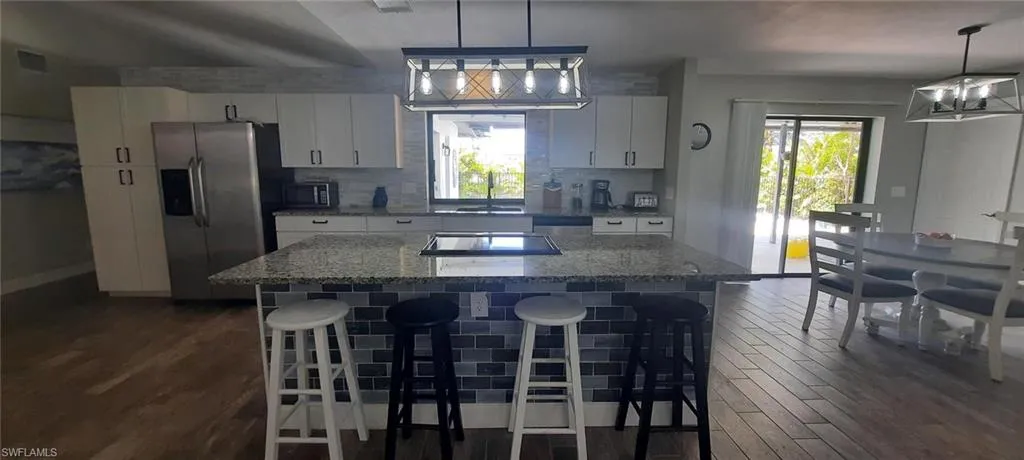 Kitchen with appliances with stainless steel finishes, a healthy amount of sunlight, a kitchen island, and white cabinets