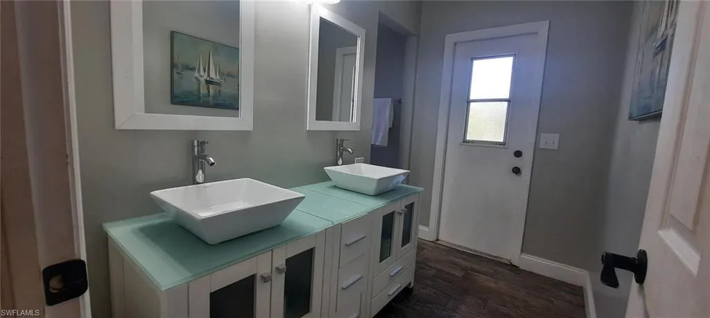 Bathroom featuring double vanity, tile floors, a sink, and baseboards
