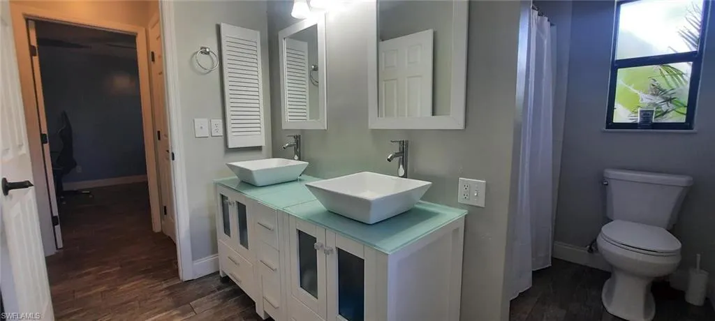 Full bathroom with toilet, baseboards, a sink, and tile floors
