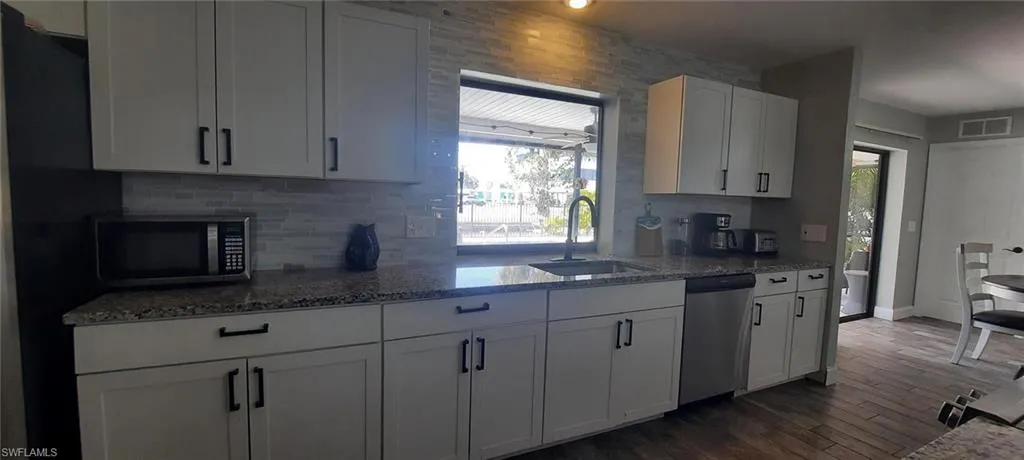 Kitchen with visible vents, decorative backsplash, light stone countertops, stainless steel appliances, and a sink