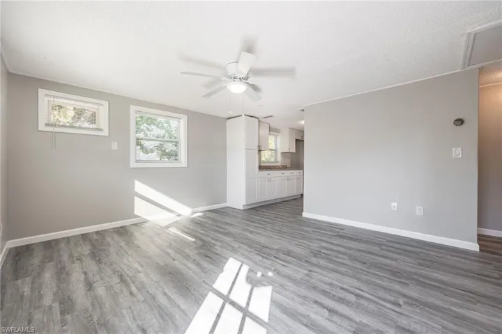 Unfurnished living room with dark wood-type flooring, a textured ceiling, and ceiling fan