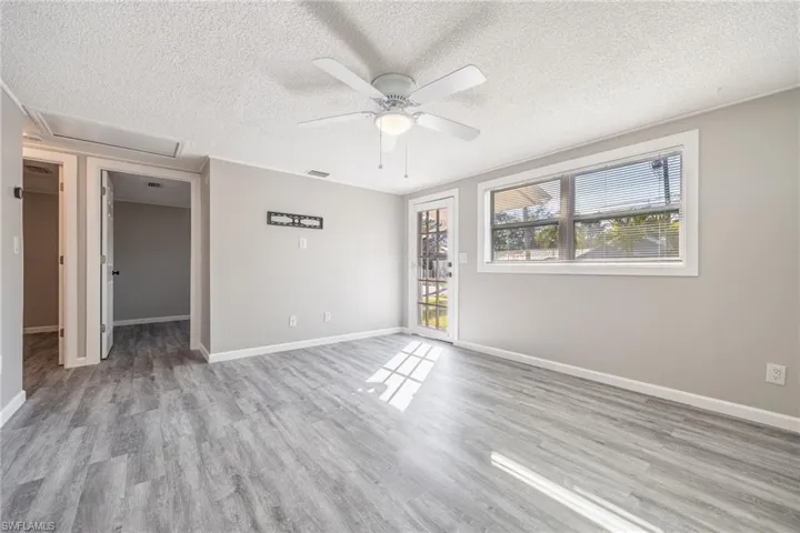 Empty room featuring ceiling fan, a textured ceiling, and light wood-type flooring