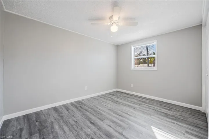 Unfurnished room featuring hardwood / wood-style flooring, ornamental molding, a textured ceiling, and ceiling fan