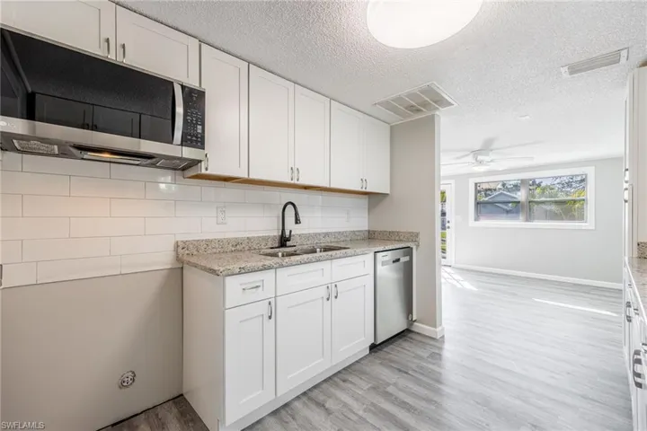 Kitchen featuring stainless steel appliances, sink, white cabinets, and light hardwood / wood-style flooring