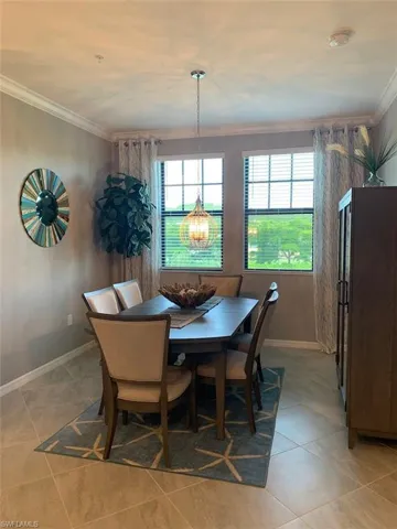 Dining room with crown molding, light tile patterned floors, and a chandelier