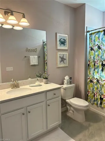 Full guest bathroom featuring tile patterned flooring, vanity, toilet, and shower / tub combo with curtain