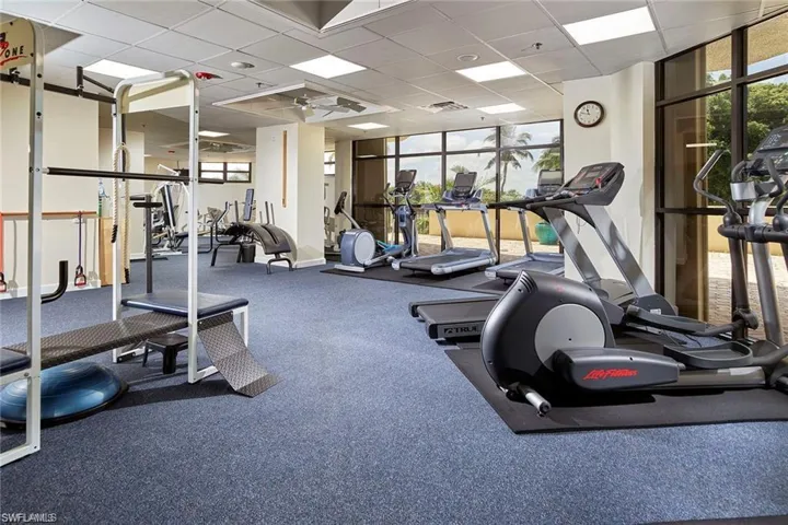 Workout area featuring expansive windows, plenty of natural light, a drop ceiling, and ceiling fan