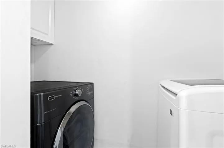 Washroom featuring independent washer and dryer and cabinet space