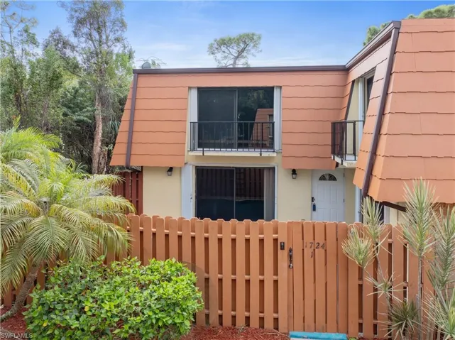 View of front facade with a balcony, a fenced front yard, a gate, and stucco siding