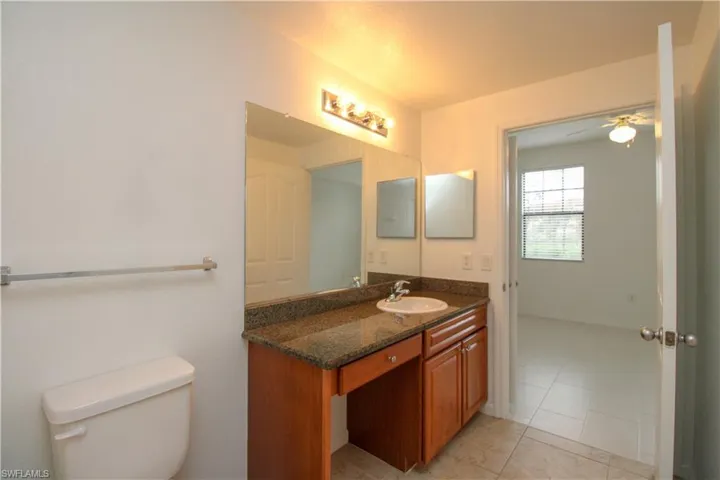 Bathroom with ceiling fan, tile patterned flooring, vanity, and toilet