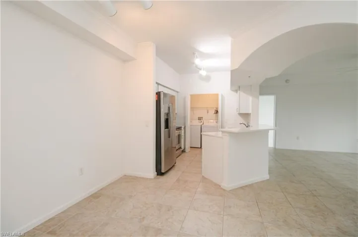 Kitchen featuring kitchen peninsula, white cabinetry, crown molding, and stainless steel refrigerator with ice dispenser