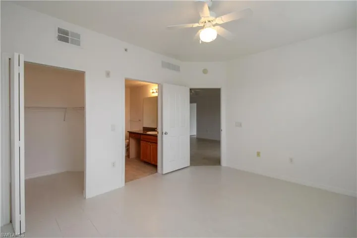 Unfurnished bedroom with connected bathroom, a closet, a spacious closet, and ceiling fan