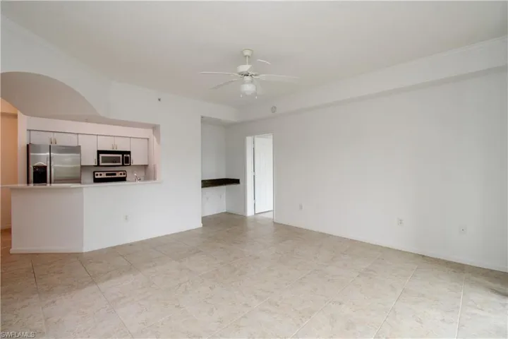 Unfurnished living room featuring ceiling fan and crown molding